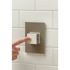 a person pressing the button on a wall mounted light switch in a white tiled bathroom