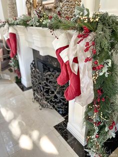 christmas stockings hanging from the mantle in front of a fire place with greenery and berries