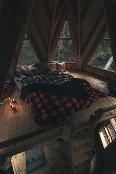 a bed in the middle of a room with wooden flooring and windows above it