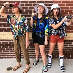 three young women standing next to each other in front of a brick wall with their mouths open