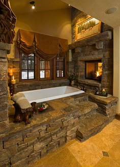 a bath tub sitting next to a fireplace in a room with stone walls and windows