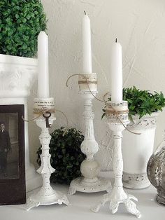 three white candles sitting on top of a table next to a potted green plant