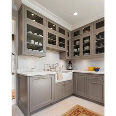 a kitchen with gray cabinets and white counter tops