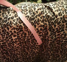 a leopard print bag with a pink ribbon on it