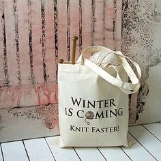 a white bag sitting on top of a wooden floor next to a wall with a knitting needle in it