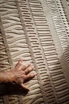 a person's hand on top of a wall made out of sand