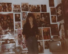 a woman standing in front of a wall full of pictures and posters on the wall