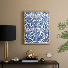 a blue and white wall hanging above a black table with a gold lamp on it