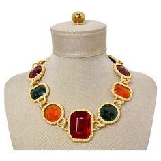 Make a bold statement with this exquisite 1980s Chanel-Like Colorful Jewel-Tone Costume Statement Necklace. Featuring an array of vibrant orangey-yellow, lush green, and deep red faux jewels, this necklace is the perfect accessory for adding a pop of color to any attire. Surrounding the jewels are shimmering gold foil-like gold-tone chains that enhance the necklace’s luxurious aura, reminiscent of high-fashion 80s couture. This vibrant piece can be stylishly paired with a fitted black dress from 80s Couture, Techno Art, Hermes Kelly Bag, Choker Collar Necklace, Fashion 80s, Versace Jewelry, Vintage Versace, Chanel Logo, Bracelet Love