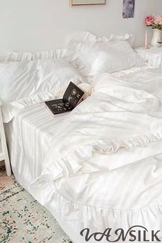 a white bed with ruffled bedspread and pillows