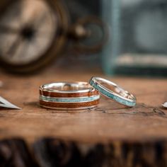 two wedding rings sitting on top of a wooden table