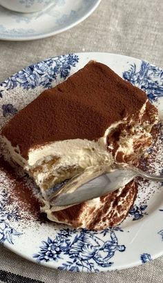 a piece of cake on a blue and white plate with a silver spoon in it