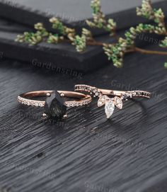 three different types of rings on top of a wooden table with greenery in the background