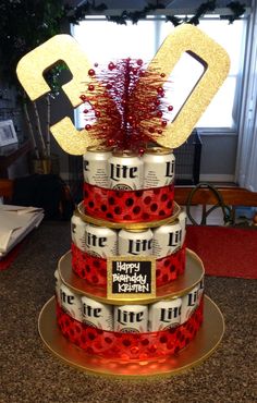 a three tiered cake made out of cans with red and gold decorations on top