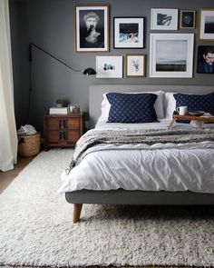 a bed sitting in a bedroom next to a window with pictures on the wall above it