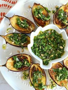 a white plate topped with grilled eggplant covered in pesto and pine nuts