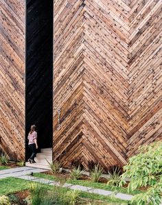 a woman is sitting in the doorway of a building made out of wood planks