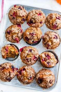 muffins with cranberries and powdered sugar are on a baking tray