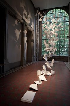 an art exhibit with paper falling from the ceiling