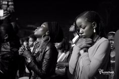 two women standing next to each other in front of a crowd with their hands together