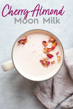 an overhead view of a cup of cherry almond moon milk with rose petals on top