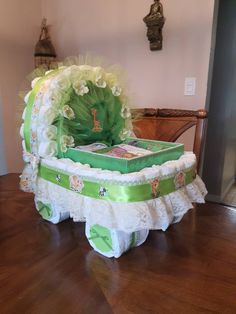 a green and white baby crib with flowers on the top, sitting on a wooden floor