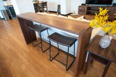 a table with two stools next to it and a vase filled with yellow flowers