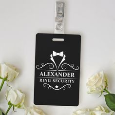 a black luggage tag with a white bow tie and the words alexandder ring security on it