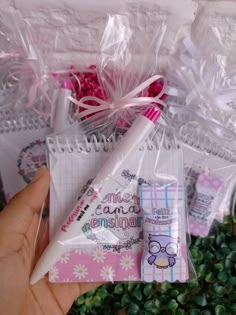 a hand holding a notepad and pen in front of some plastic bags with writing on them