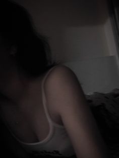 a blurry image of a woman in a tank top sitting on a bed looking at her cell phone