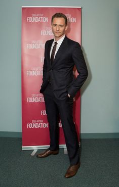 a man wearing a suit and tie standing in front of a red sign that says foundation