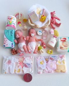 several baby items are laid out on a white tablecloth, including diapers and toys