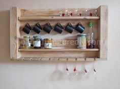 a wooden shelf with wine glasses hanging from it's sides and cups on the shelves