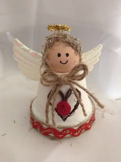 a small angel figurine sitting on top of a white surface with a red button