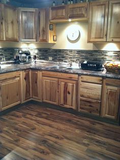 a kitchen with wooden cabinets and granite counter tops, along with wood flooring in the middle