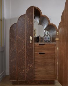 a wooden cabinet sitting in the corner of a room next to a mirror and door