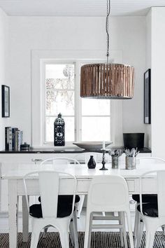 a dining room table with white chairs and a chandelier hanging from the ceiling