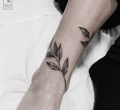 a woman's foot with a leaf tattoo on the left side of her leg