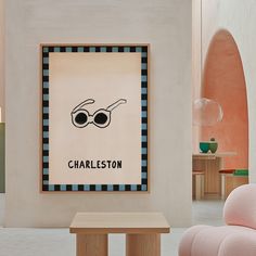 a chair and table in a room with a poster on the wall above it that says charleston