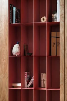 a red book shelf with books and magazines on it's shelves in a room