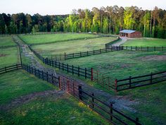 an aerial view of a farm with a barn in the distance and trees around it