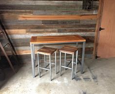 three stools and a table in front of a wooden wall