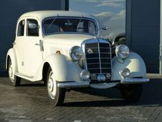 an old white car parked in front of a building