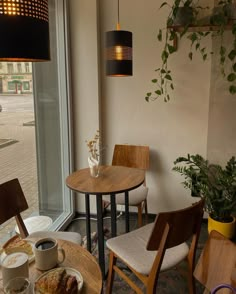 a table and chairs in front of a window with a potted plant next to it