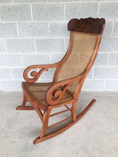 a wooden rocking chair sitting on top of a cement floor next to a brick wall