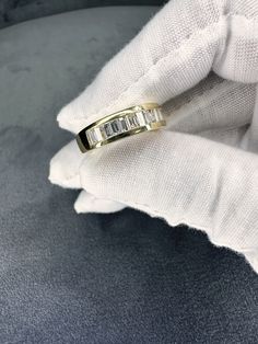 a gold ring with three baguets in it on top of a white glove