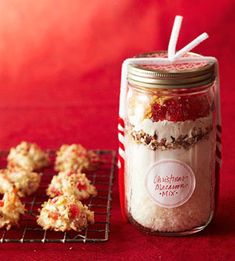 a jar filled with cookies and marshmallows next to a cooling rack on a red surface