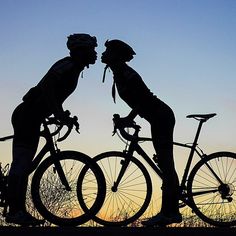 two silhouettes of people on bicycles with trees in the background