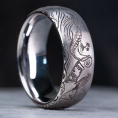 a silver ring with an image of a dragon on the inside and inlayed to it