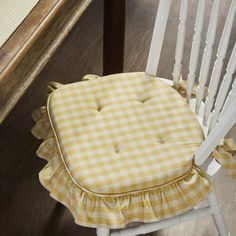 a white rocking chair with yellow gingham ruffled seat cover on the back